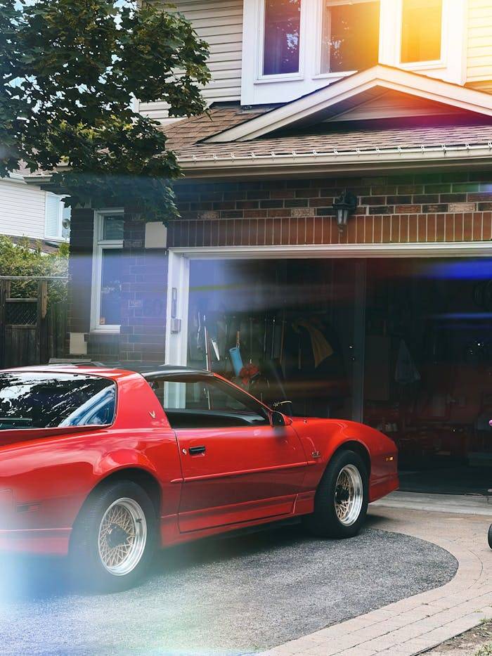 services-01 Vintage red sports car parked in front of a garage with sunlight flare effect.