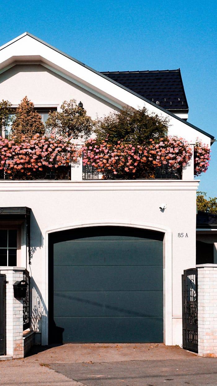ours-journey Stylish urban house in Cluj-Napoca featuring a garage and flowering balcony under a clear blue sky.