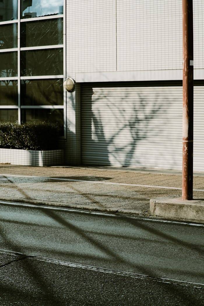 services-img An urban street scene featuring building shadows and a closed garage door.