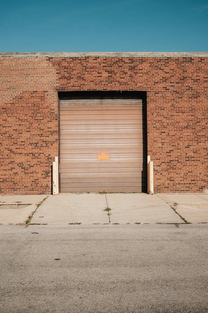 services-03 A brick warehouse with a closed roller door under a clear blue sky.
