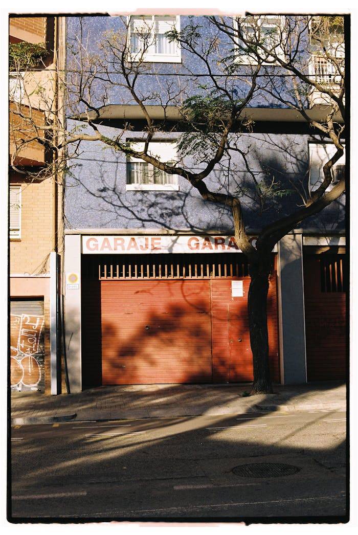 gallery-2 A city garage entrance with shadow patterns from a tree in sunlight.