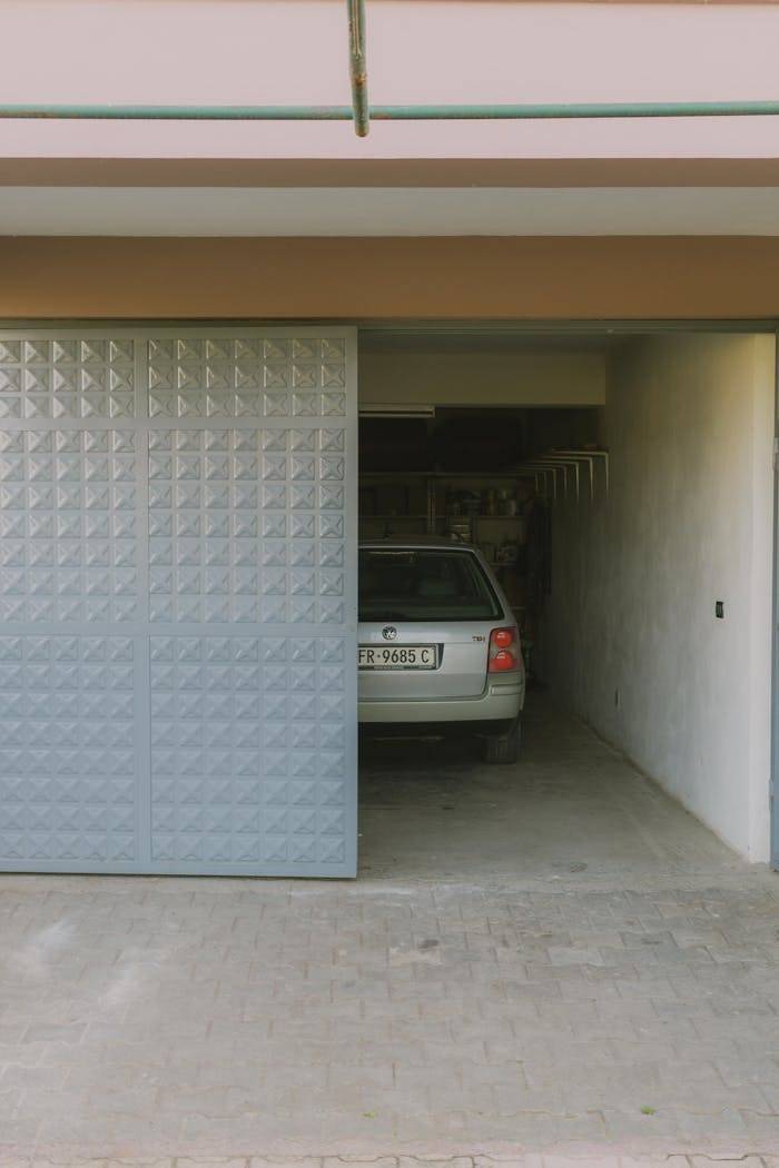 about-01 Partially open garage with parked car visible inside, featuring a modern sliding door design.