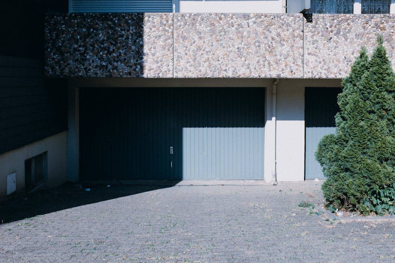 why-choose-us Contemporary house facade featuring dual garage doors and a lush green tree.
