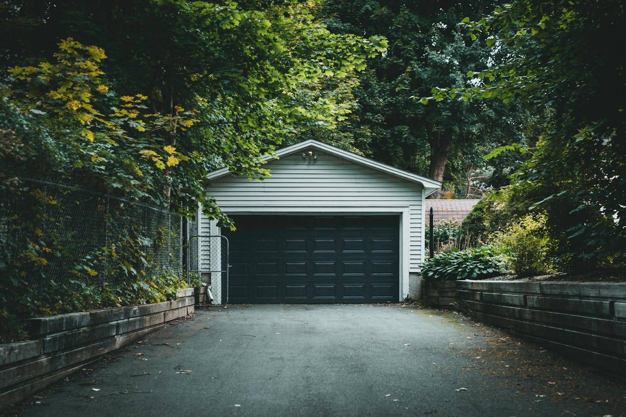 services-02 A scenic garage with lush greenery and a driveway, perfect for residential and nature-themed content.