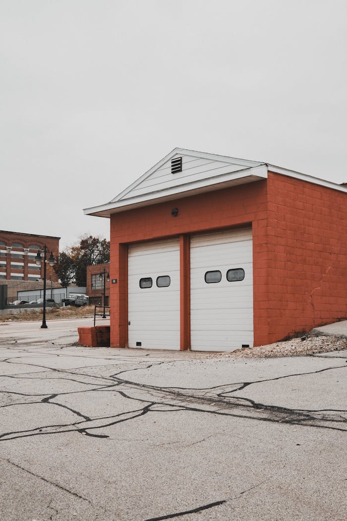 digital Urban scene capturing a red-brick garage building with double doors, set on a quiet street.