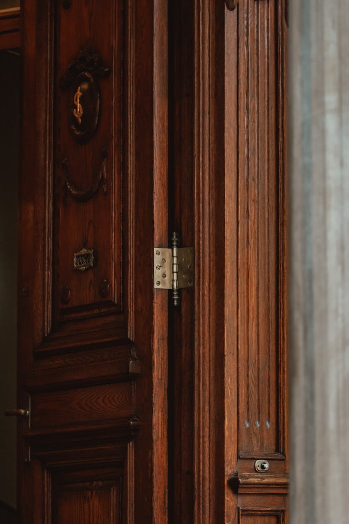 A luxurious and detailed wooden doorway with classic design elements and a visible hinge.