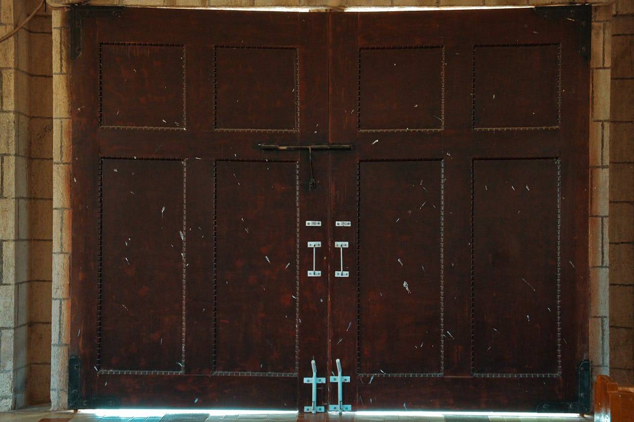 services-02 A set of rustic wooden double doors featuring metal latches and a textured surface, ideal for architectural themes.