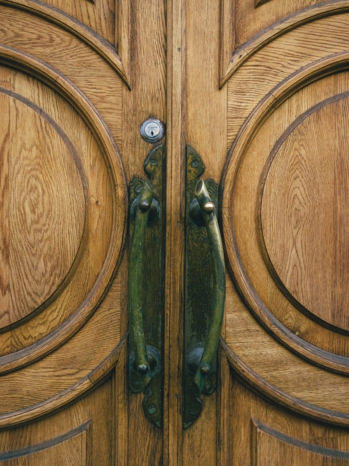why-choose-us Close-up of a beautifully crafted wooden door with brass handles, showcasing intricate design and craftsmanship.